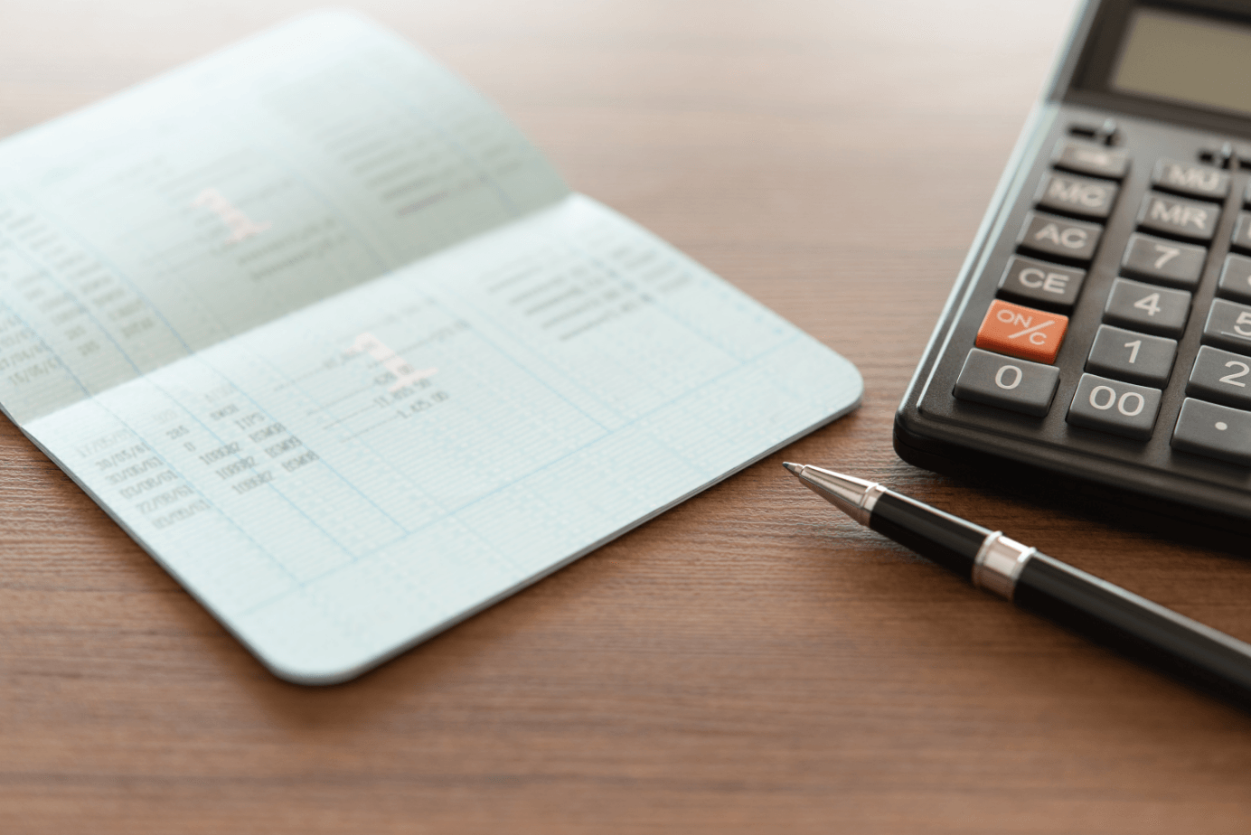 A pen is sitting next to a calculator on a table.